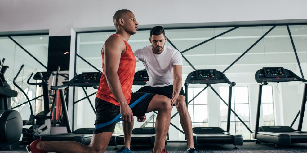 attentive trainer controlling african american sportsman exercis